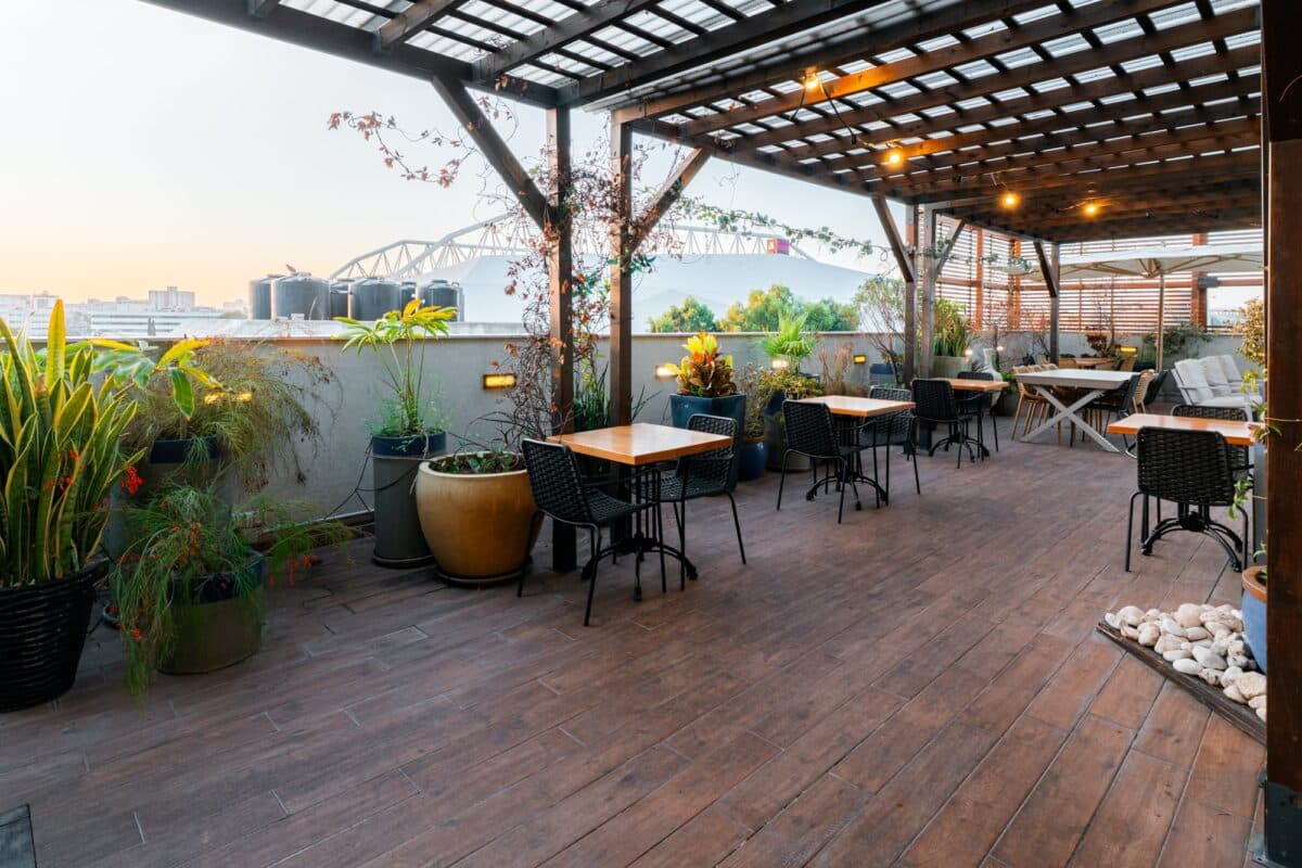 Abba Hotel Tel Aviv rooftop seating under a pergola with tropical plants and a city view