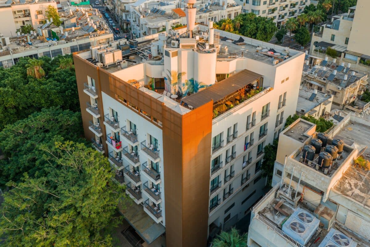 Close aerial view of Abba Hotel Tel Aviv-Yafo with copper façade balconies and a green rooftop terrace